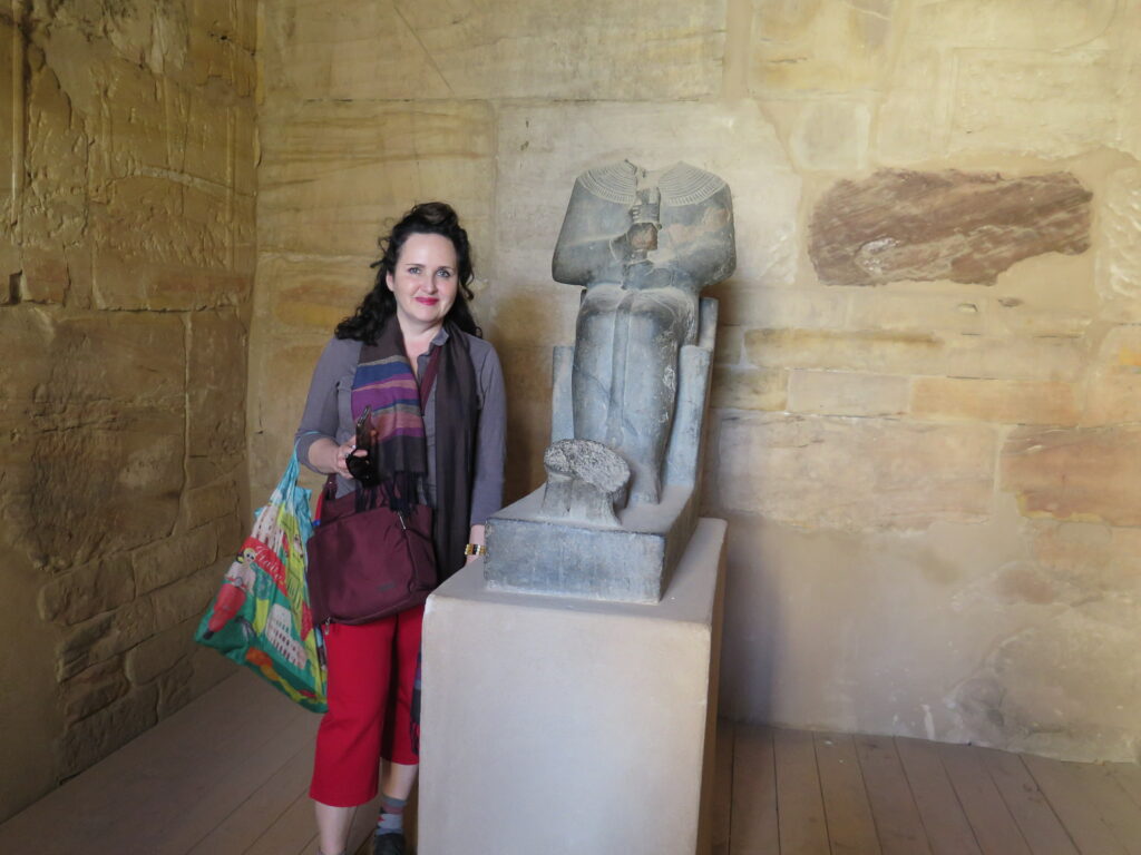Laura stands beside headless granite statue of god Ptah at Ptah Temple, Karnak
